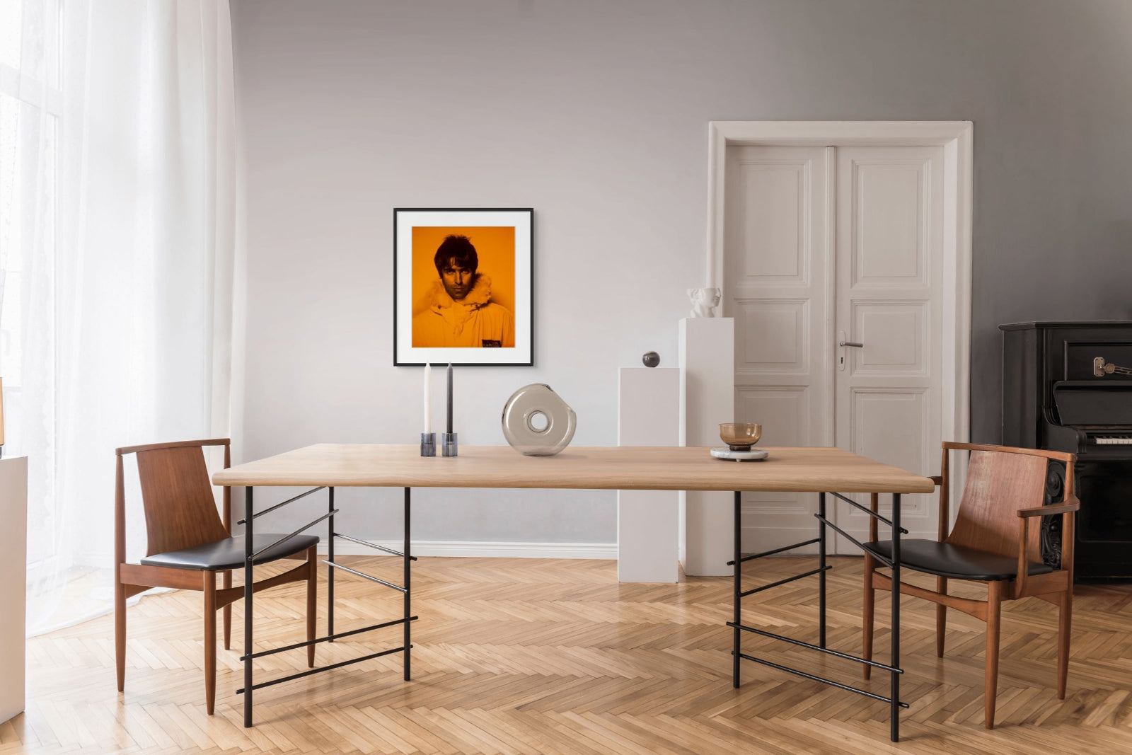Modern dining room with wooden table and chairs, framed Liam Gallagher artwork on the wall.